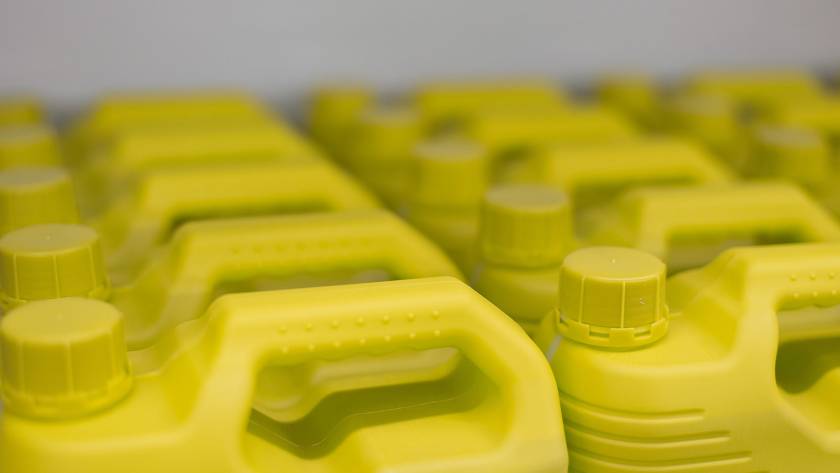 Close-up view of yellow plastic motor oil containers neatly arranged on a shelf in an auto service shop.